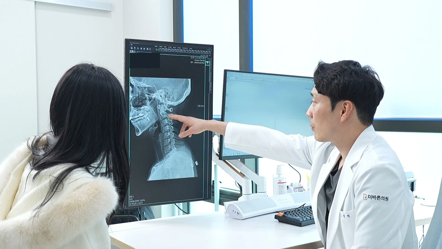 원장님이 컴퓨터의 X-ray 영상을 보며 환자에게 설명하는 모습